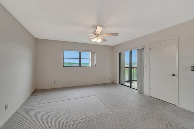 spare room with ceiling fan, plenty of natural light, baseboards, and light colored carpet