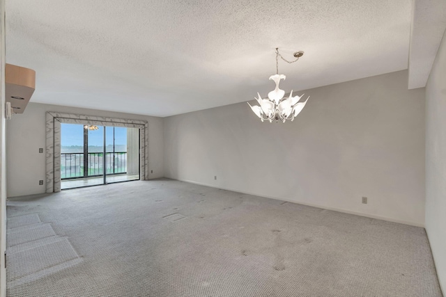 unfurnished room featuring a textured ceiling, carpet floors, and an inviting chandelier