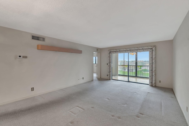 carpeted spare room featuring visible vents and a textured ceiling