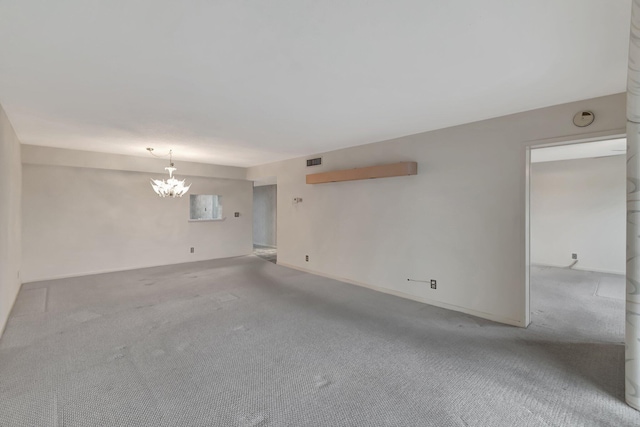 carpeted empty room with baseboards, visible vents, and a notable chandelier