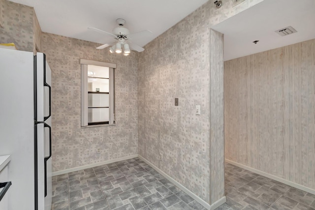 unfurnished room with baseboards, visible vents, and ceiling fan