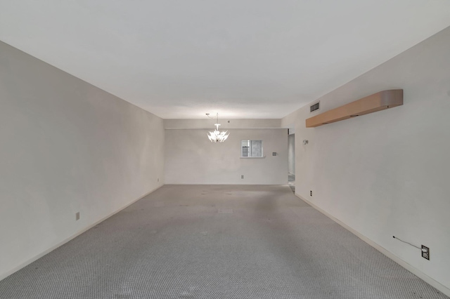 empty room with light carpet, visible vents, and a notable chandelier