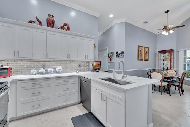 kitchen with sink, appliances with stainless steel finishes, white cabinetry, backsplash, and kitchen peninsula