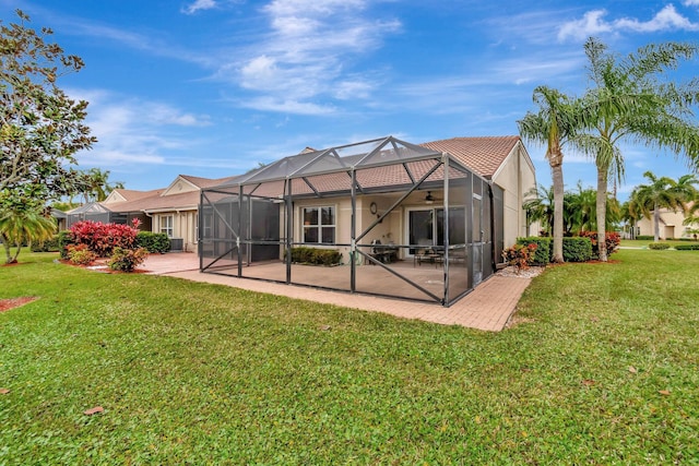 back of property featuring a yard, a patio area, and glass enclosure