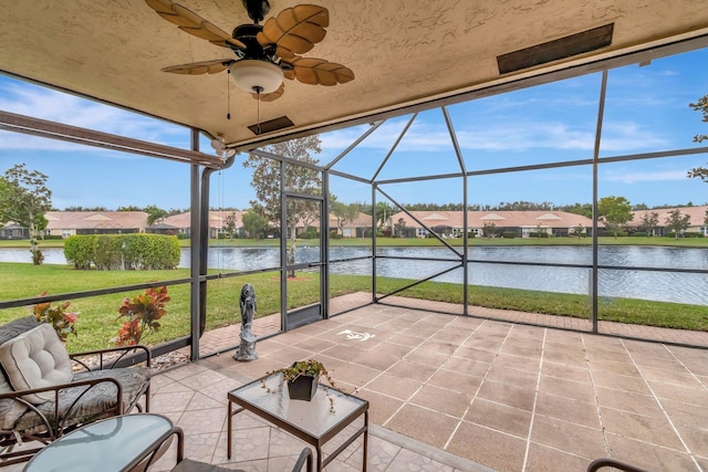 unfurnished sunroom with ceiling fan and a water view