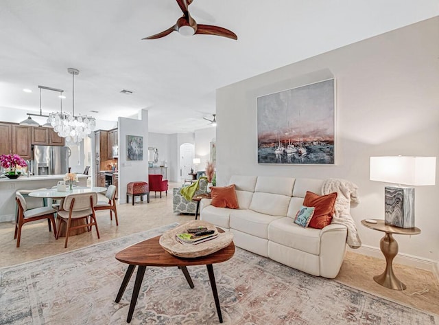 living area with ceiling fan with notable chandelier, arched walkways, and baseboards