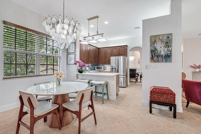 dining room featuring arched walkways, a toaster, a notable chandelier, recessed lighting, and baseboards