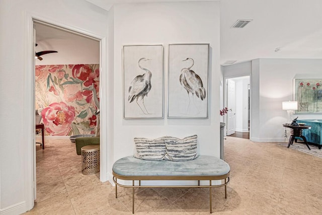 hall featuring light tile patterned floors, visible vents, and baseboards