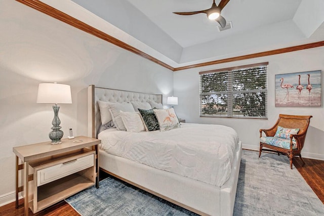 bedroom with a raised ceiling, visible vents, dark wood-type flooring, a ceiling fan, and baseboards