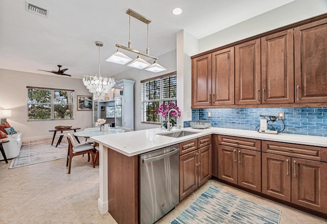 kitchen with hanging light fixtures, stainless steel dishwasher, a peninsula, and a sink