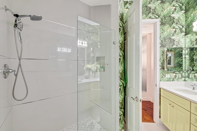 bathroom featuring wallpapered walls, walk in shower, and vanity