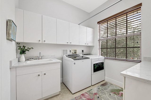 washroom featuring washer and clothes dryer, a sink, cabinet space, and baseboards