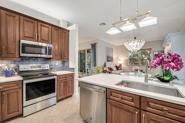 kitchen with light countertops, appliances with stainless steel finishes, a sink, and pendant lighting