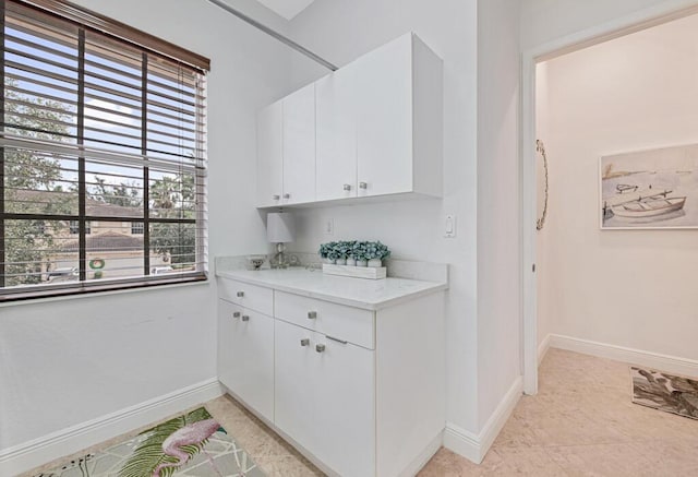 interior space featuring light stone counters, white cabinetry, and baseboards