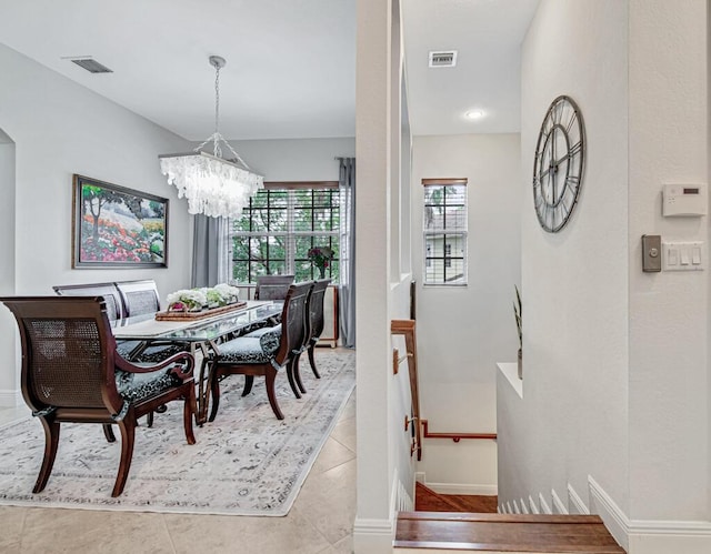 dining space featuring a chandelier, light tile patterned flooring, visible vents, and baseboards