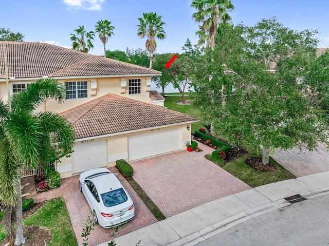 view of front of home featuring a garage, decorative driveway, a tile roof, and stucco siding