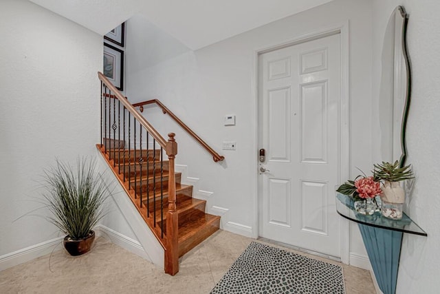 foyer featuring light tile patterned flooring, stairway, and baseboards