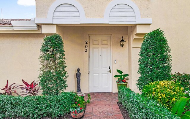 property entrance featuring a tiled roof and stucco siding