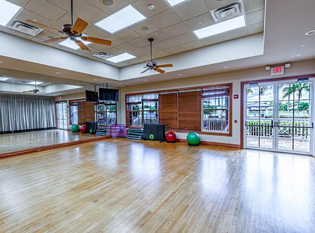 workout room with a ceiling fan, a paneled ceiling, visible vents, and light wood-style flooring