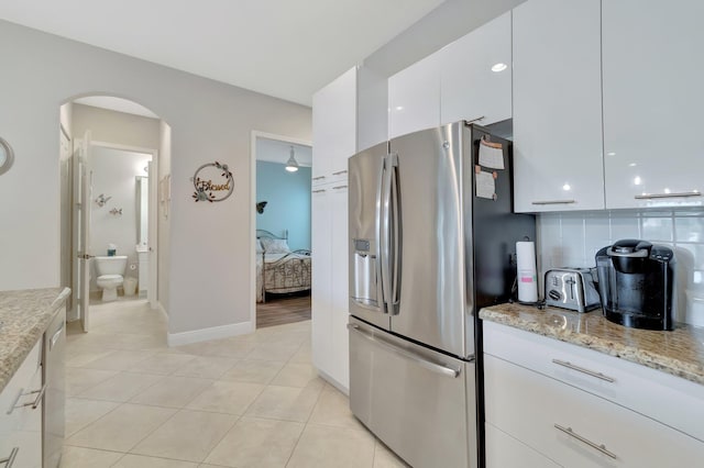 kitchen featuring light tile patterned flooring, white cabinetry, decorative backsplash, light stone counters, and stainless steel fridge with ice dispenser