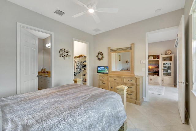 bedroom featuring ensuite bathroom, a spacious closet, light tile patterned floors, ceiling fan, and a closet