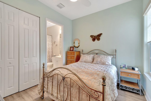 bedroom featuring ensuite bathroom, light wood-type flooring, a closet, ceiling fan, and multiple windows