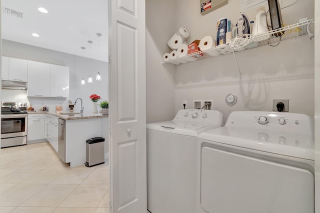 washroom featuring washing machine and dryer, sink, and light tile patterned floors