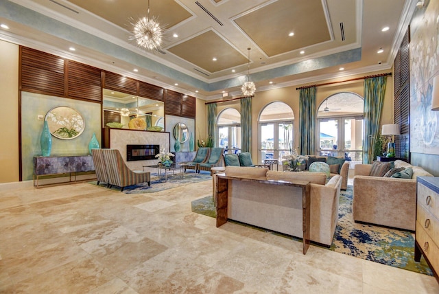 living room featuring french doors, an inviting chandelier, crown molding, a towering ceiling, and a high end fireplace