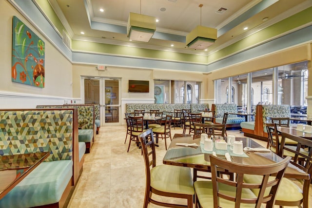 tiled dining space with crown molding, a tray ceiling, and a high ceiling