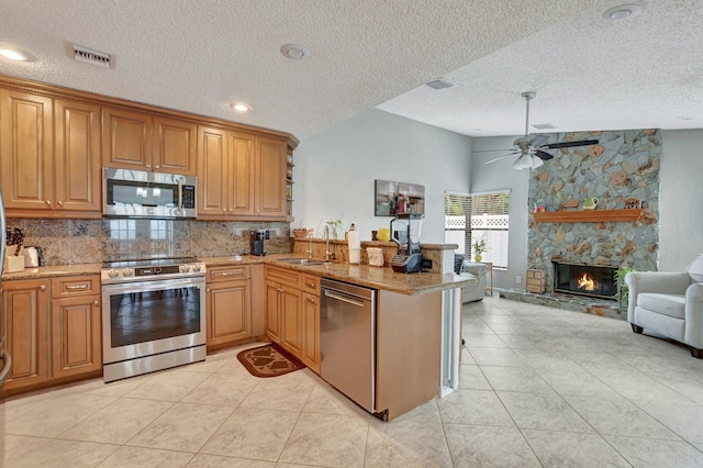 kitchen with stainless steel appliances, kitchen peninsula, sink, and light tile patterned floors