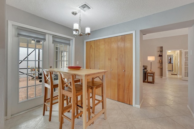 tiled dining area with a notable chandelier, french doors, and a textured ceiling