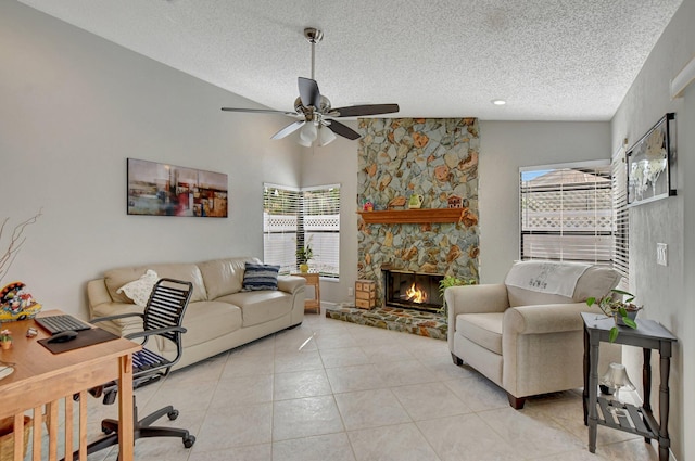 tiled living room with ceiling fan, a stone fireplace, vaulted ceiling, and a textured ceiling