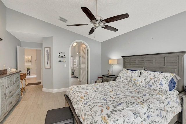 bedroom featuring ceiling fan, vaulted ceiling, light hardwood / wood-style flooring, and a textured ceiling