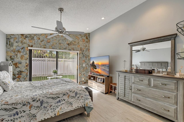 bedroom featuring ceiling fan, vaulted ceiling, a textured ceiling, and light hardwood / wood-style flooring