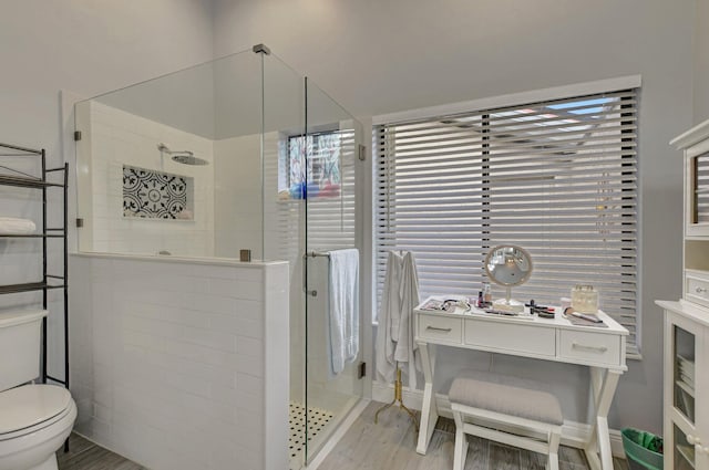 bathroom featuring hardwood / wood-style floors, a shower with shower door, and toilet