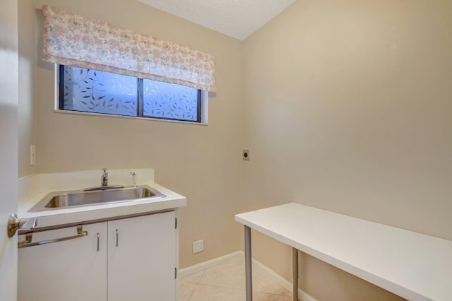 laundry area featuring electric dryer hookup, sink, light tile patterned floors, and a textured ceiling