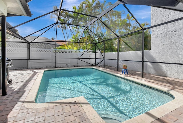 view of swimming pool featuring a patio and glass enclosure