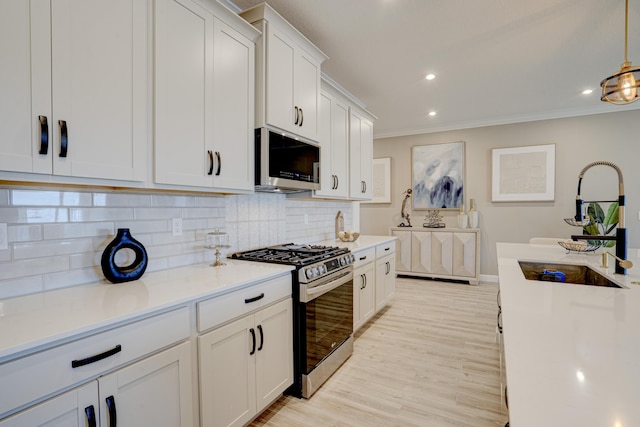 kitchen with pendant lighting, backsplash, white cabinetry, and stainless steel appliances