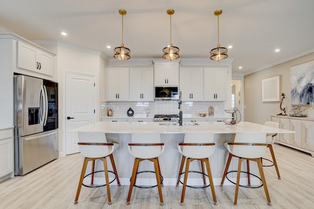 kitchen featuring a center island with sink, appliances with stainless steel finishes, pendant lighting, and white cabinets