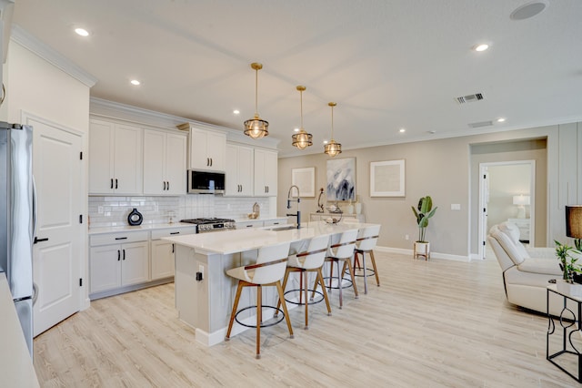 kitchen featuring a kitchen island with sink, sink, white cabinetry, and appliances with stainless steel finishes