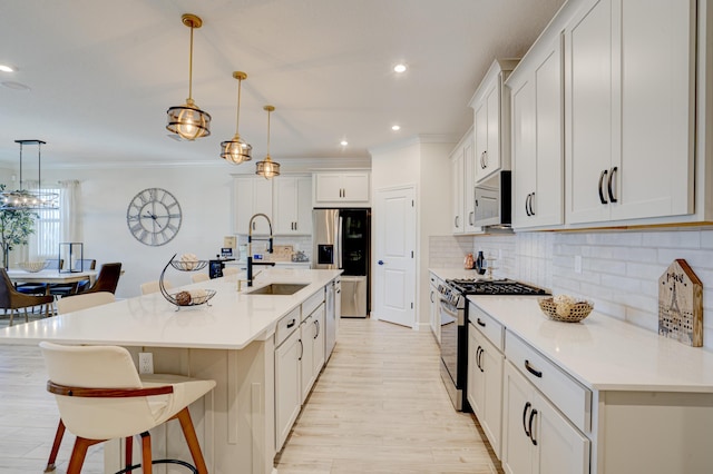 kitchen featuring sink, decorative light fixtures, an island with sink, and appliances with stainless steel finishes