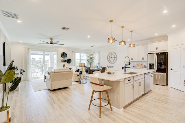 kitchen with white cabinetry, appliances with stainless steel finishes, sink, and a center island with sink