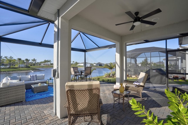 view of patio / terrace featuring a water view, ceiling fan, an outdoor hangout area, and glass enclosure