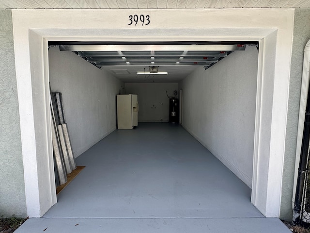 garage with a garage door opener, white refrigerator with ice dispenser, and water heater