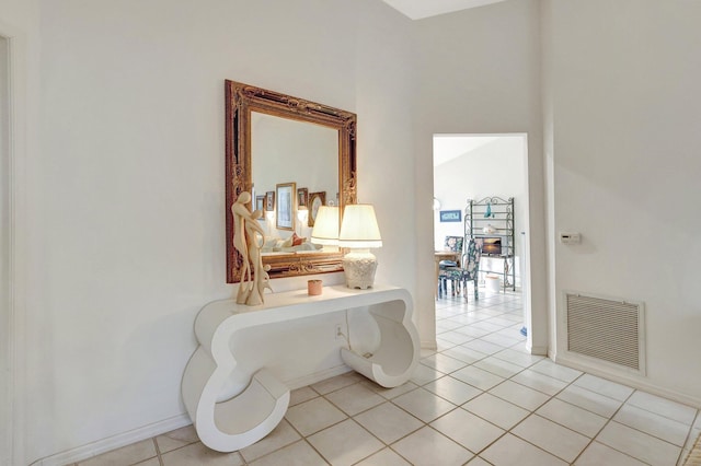 hall featuring baseboards, visible vents, and light tile patterned flooring