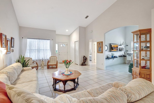 living room with arched walkways, light tile patterned floors, recessed lighting, visible vents, and high vaulted ceiling