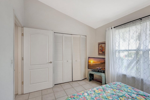 bedroom with lofted ceiling, a closet, and light tile patterned floors