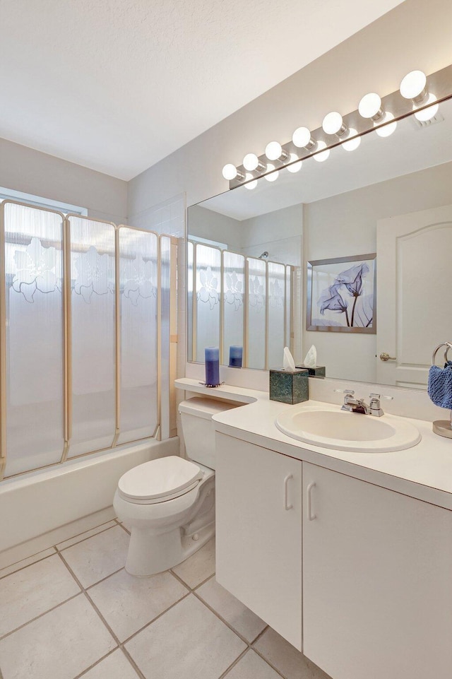 full bath featuring plenty of natural light, bath / shower combo with glass door, toilet, tile patterned flooring, and vanity