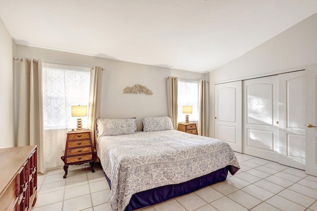 bedroom with lofted ceiling, light tile patterned floors, and a closet