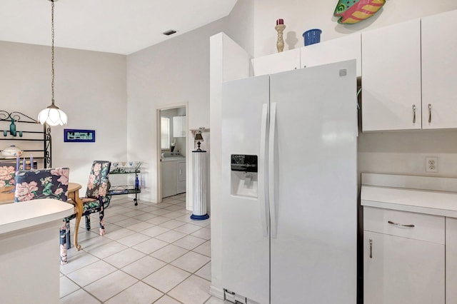 kitchen with white fridge with ice dispenser, washer and dryer, decorative light fixtures, and white cabinets